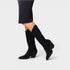 Black glittery knee-high boots worn with black pants on a light gray background