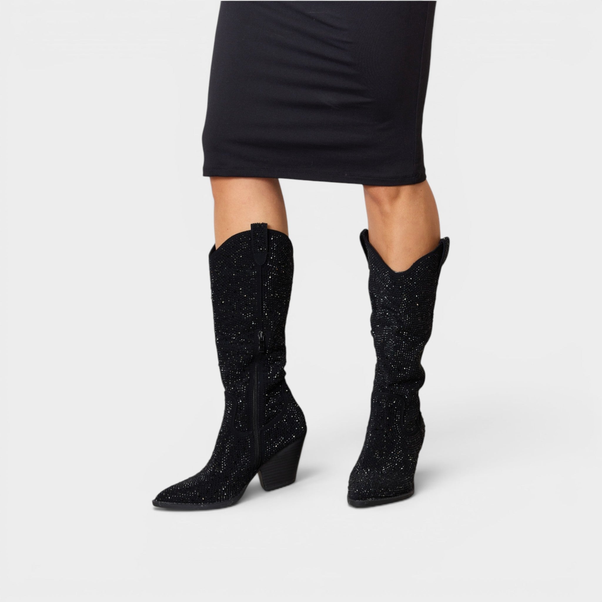 Black glittery knee-high boots worn with a black skirt on a light gray background