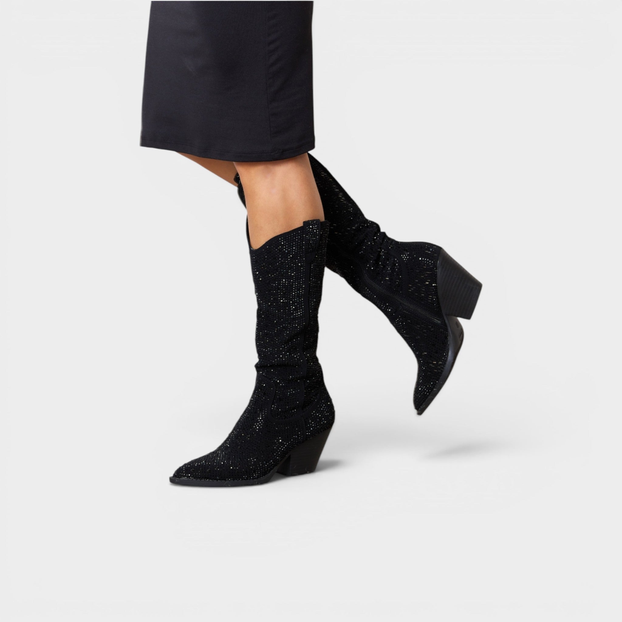 Black glittery ankle boots worn with a black skirt on a light gray background
