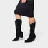 Black glittery knee-high boots worn with a black dress on a white background