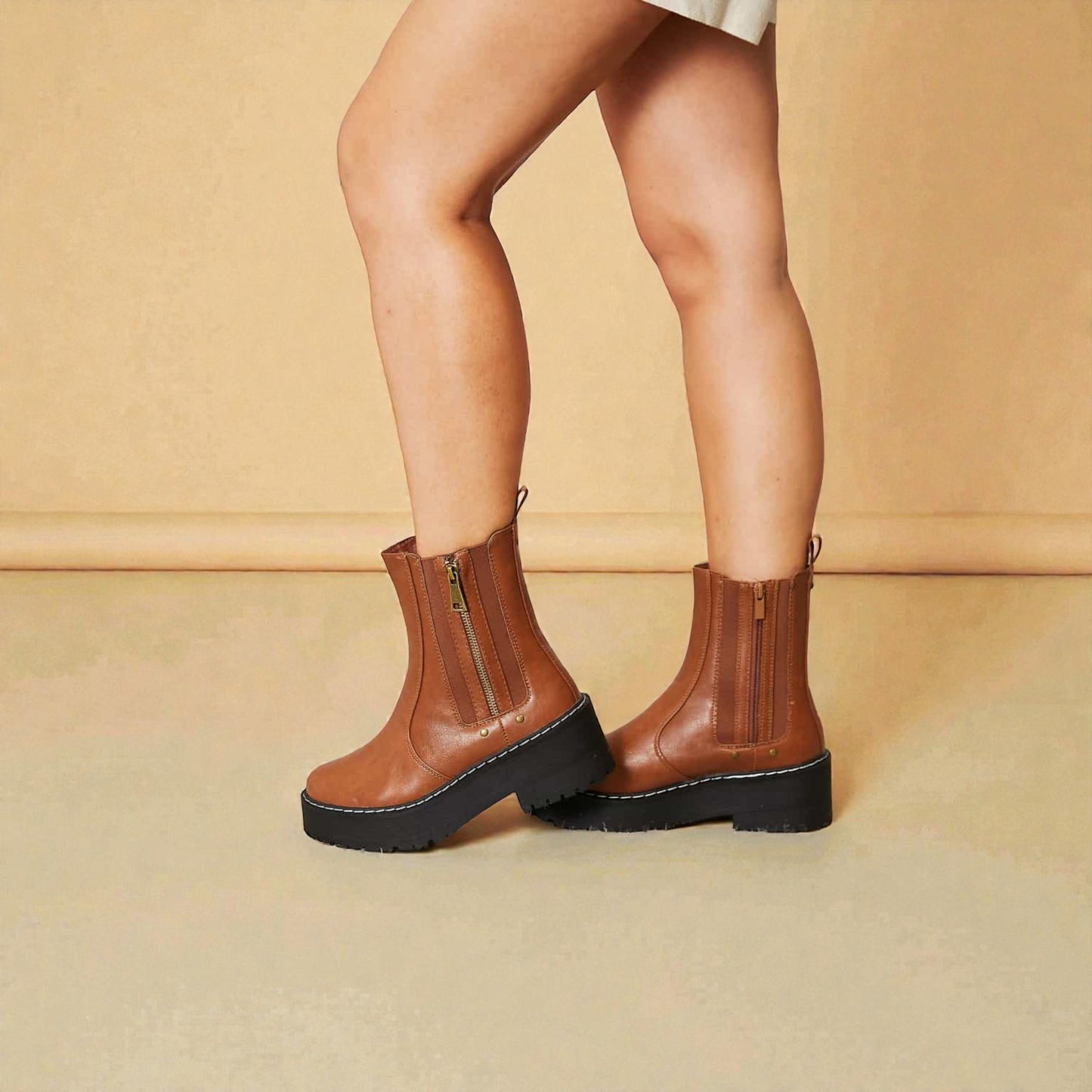Brown platform boots worn by a person on a beige background