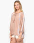 A woman modeling a loose, long-sleeve tie-neck top in a dusty rose color with light purple and yellow patterned sleeves, paired with white shorts, against a plain white background.