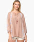 A woman modeling a loose, three-quarter sleeve top in a dusty rose color with lavender and cream floral patterned side panels and a drawstring tassel neckline, paired with light beige shorts against a plain white background.