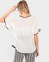 A woman shown from the back wearing a loose white textured short-sleeve top with black trim, paired with black-and-white striped pants, against a light gray studio background.