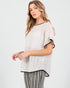 Woman wearing a beige knit top with black trim on a white background
