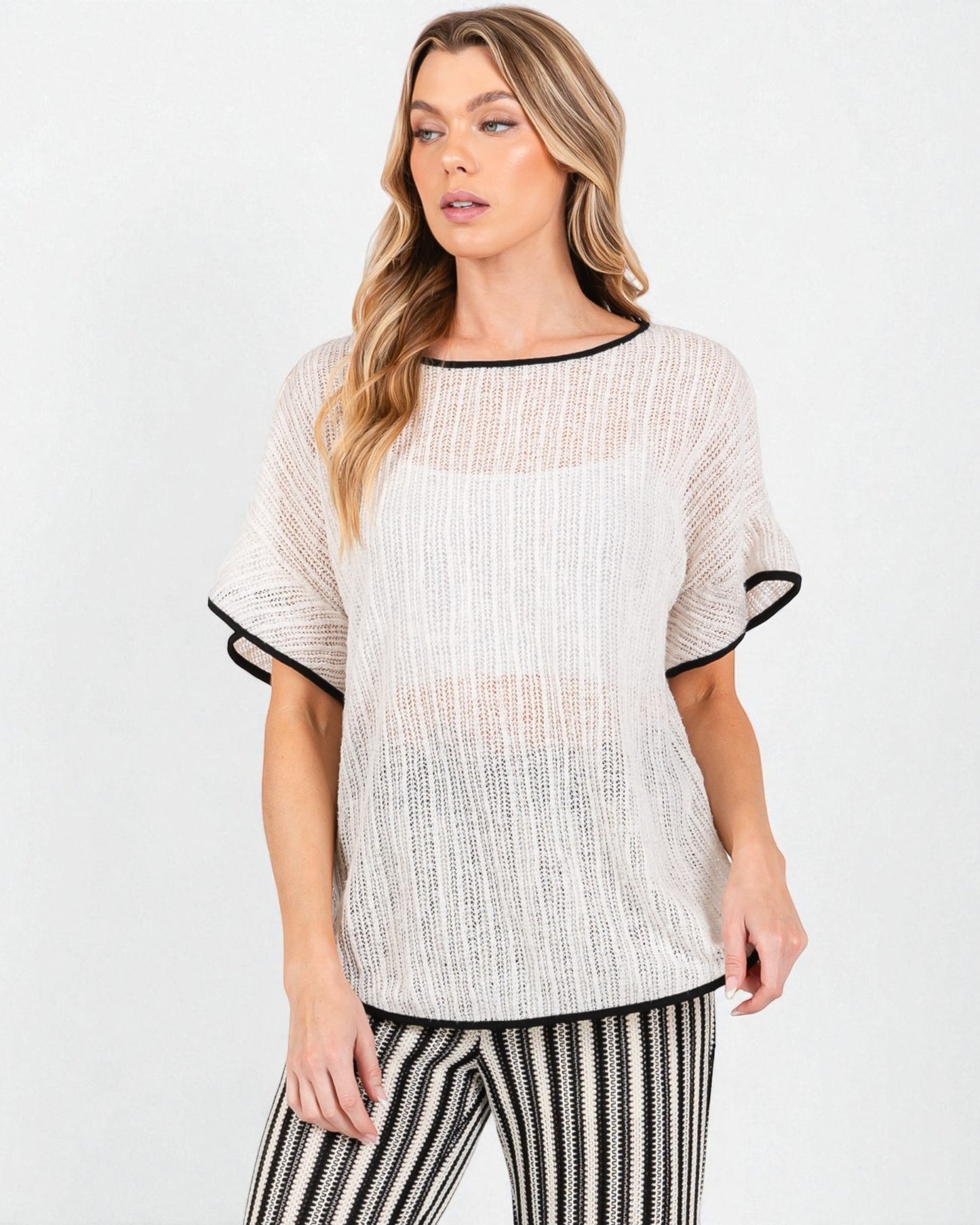 Woman wearing a white blouse with black trim on a white background