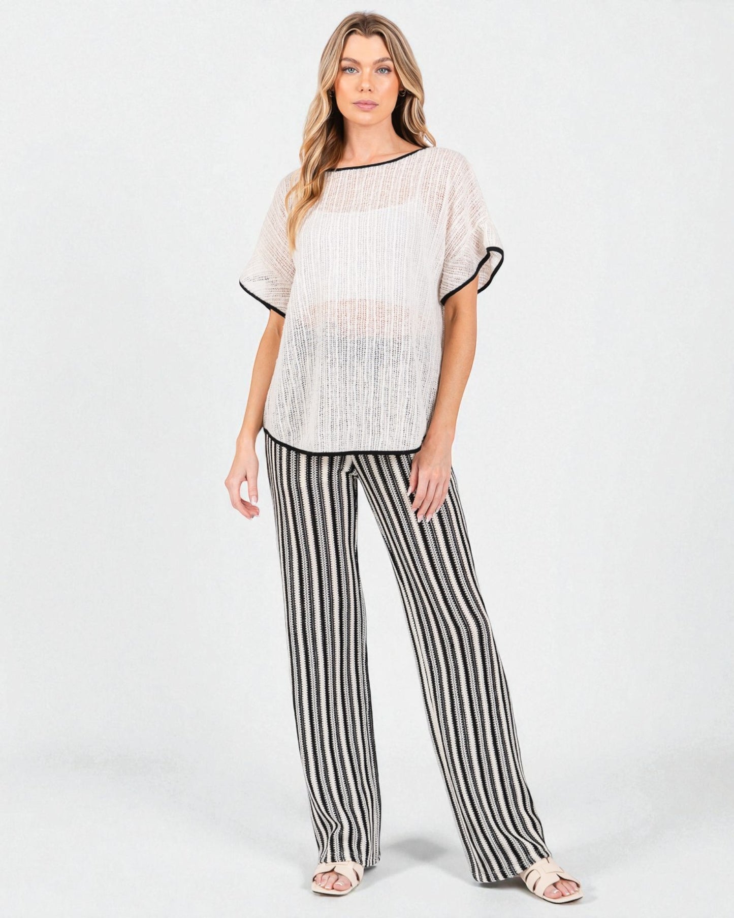 Woman wearing a textured top and striped pants on a white background