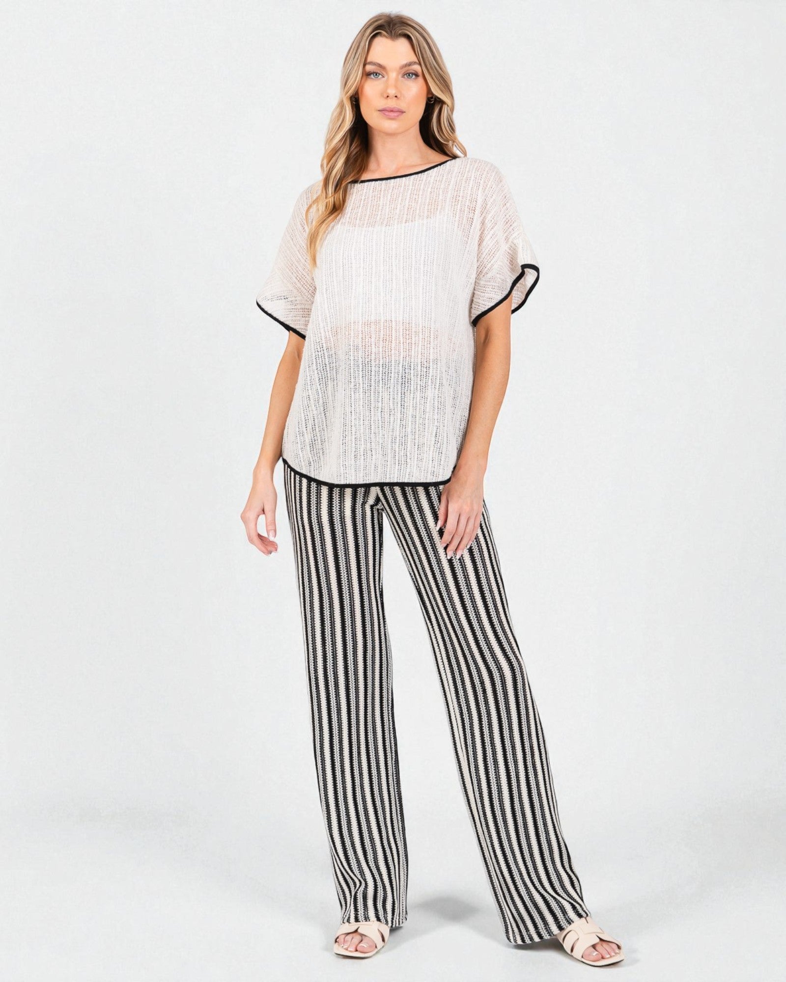 Woman wearing a textured top and striped pants on a white background