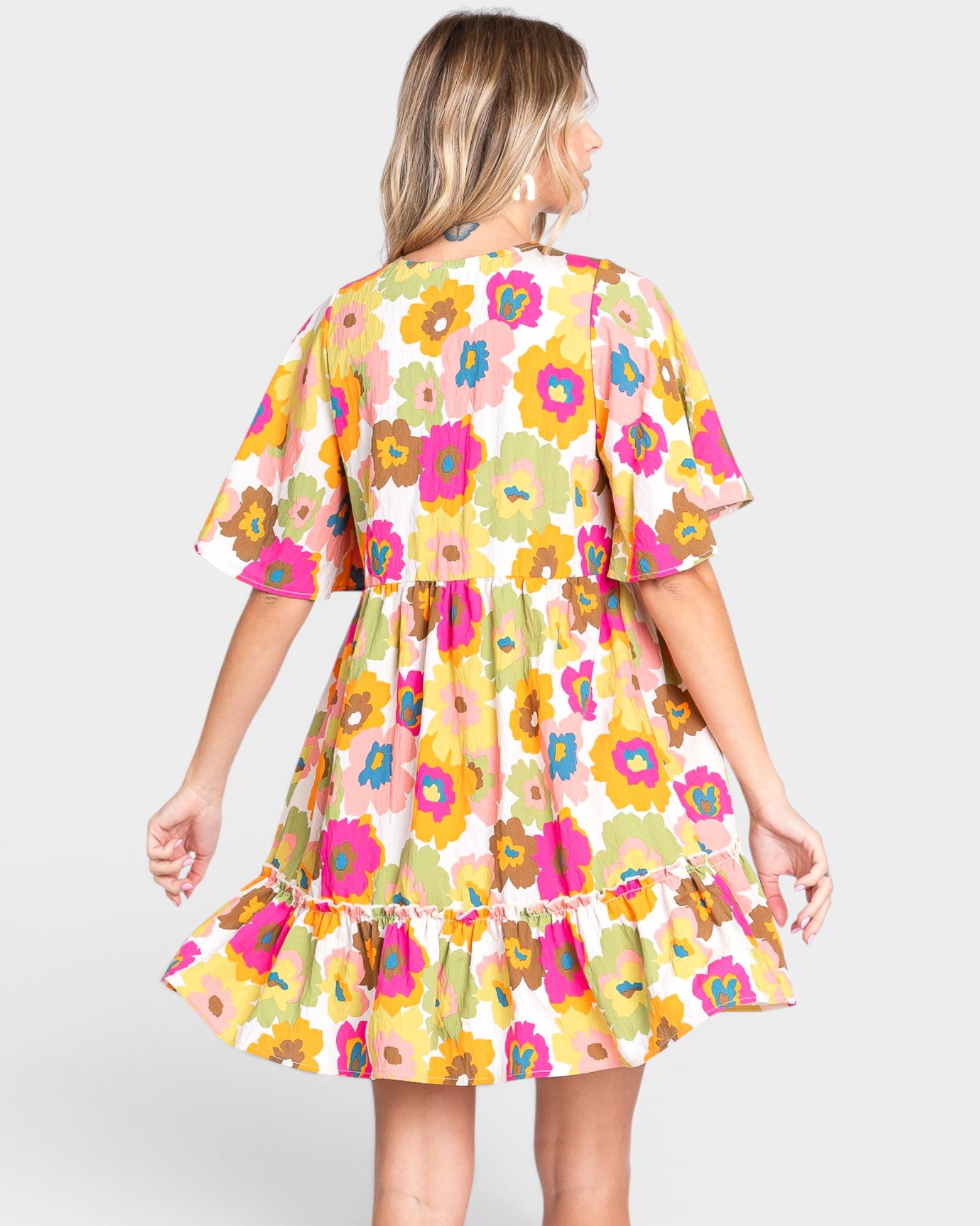 Woman wearing a colorful floral dress on a plain background