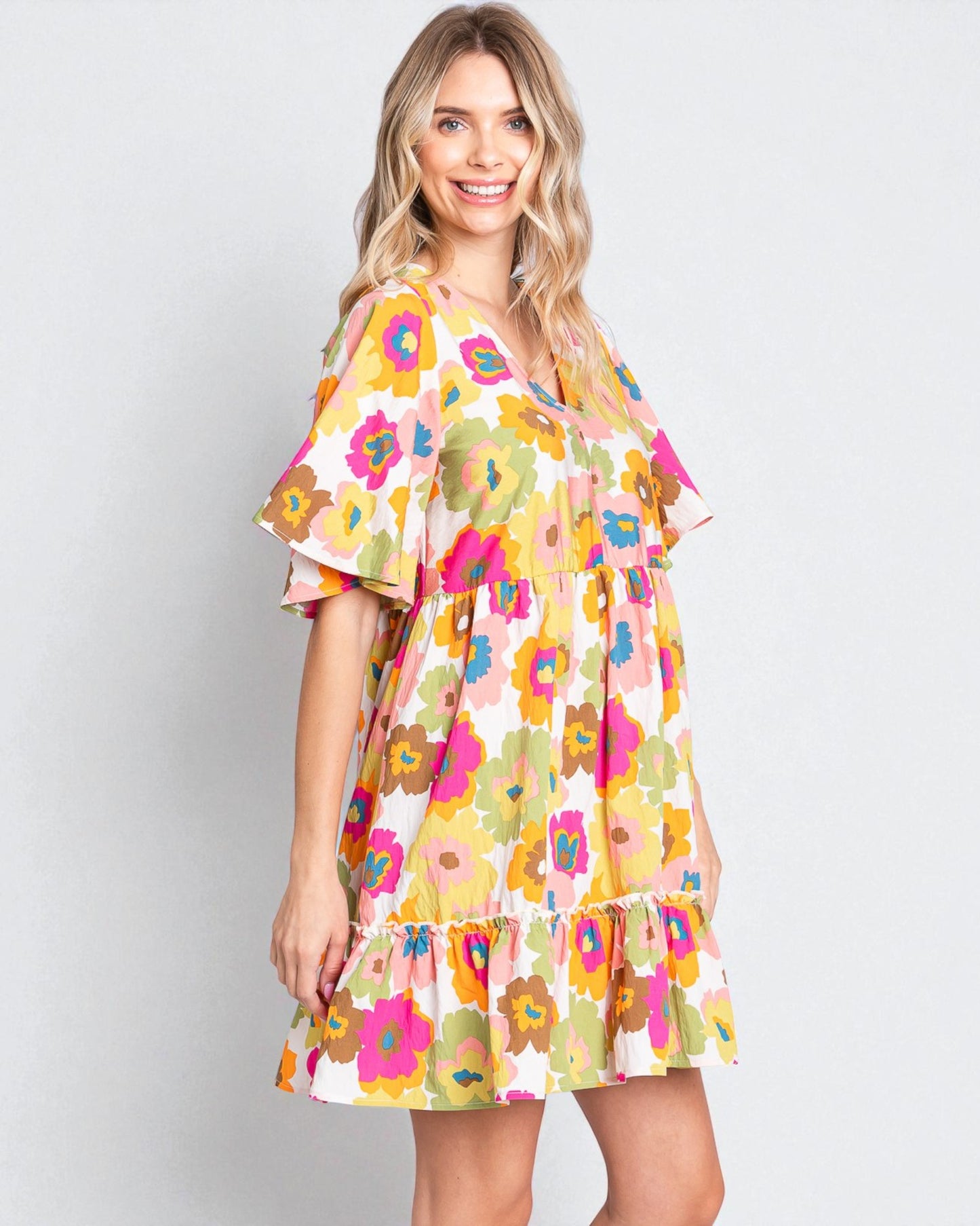 Woman wearing a colorful floral dress on a plain background