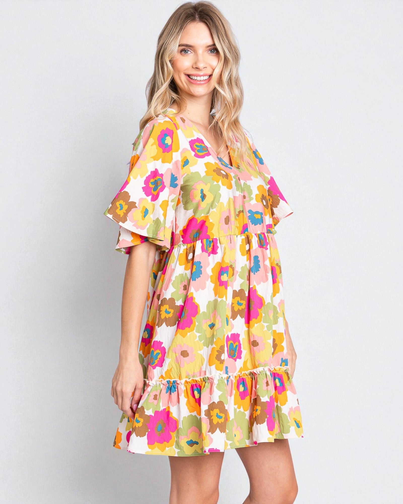 Woman wearing a colorful floral dress on a plain background