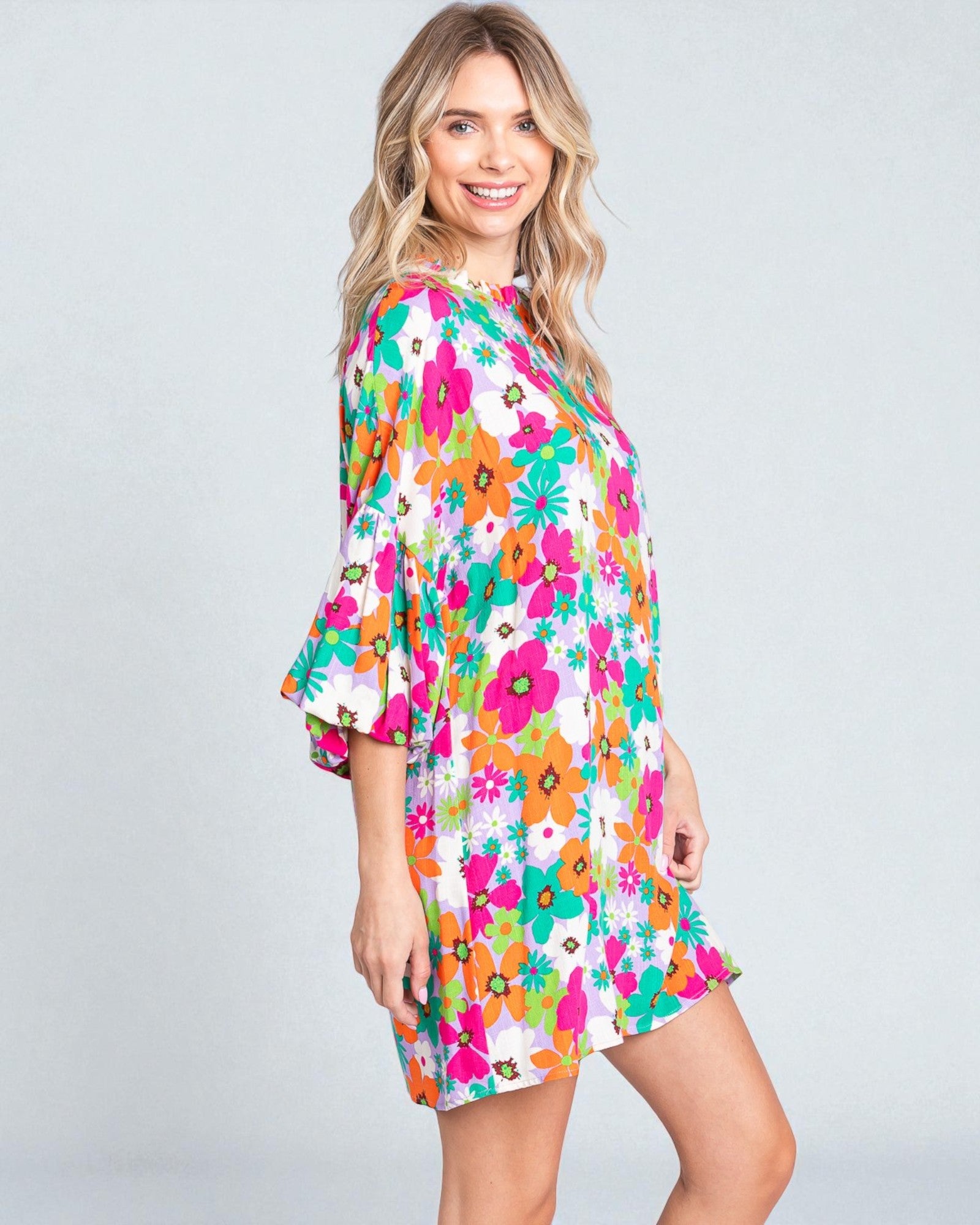 Woman wearing a colorful floral dress on a gray background