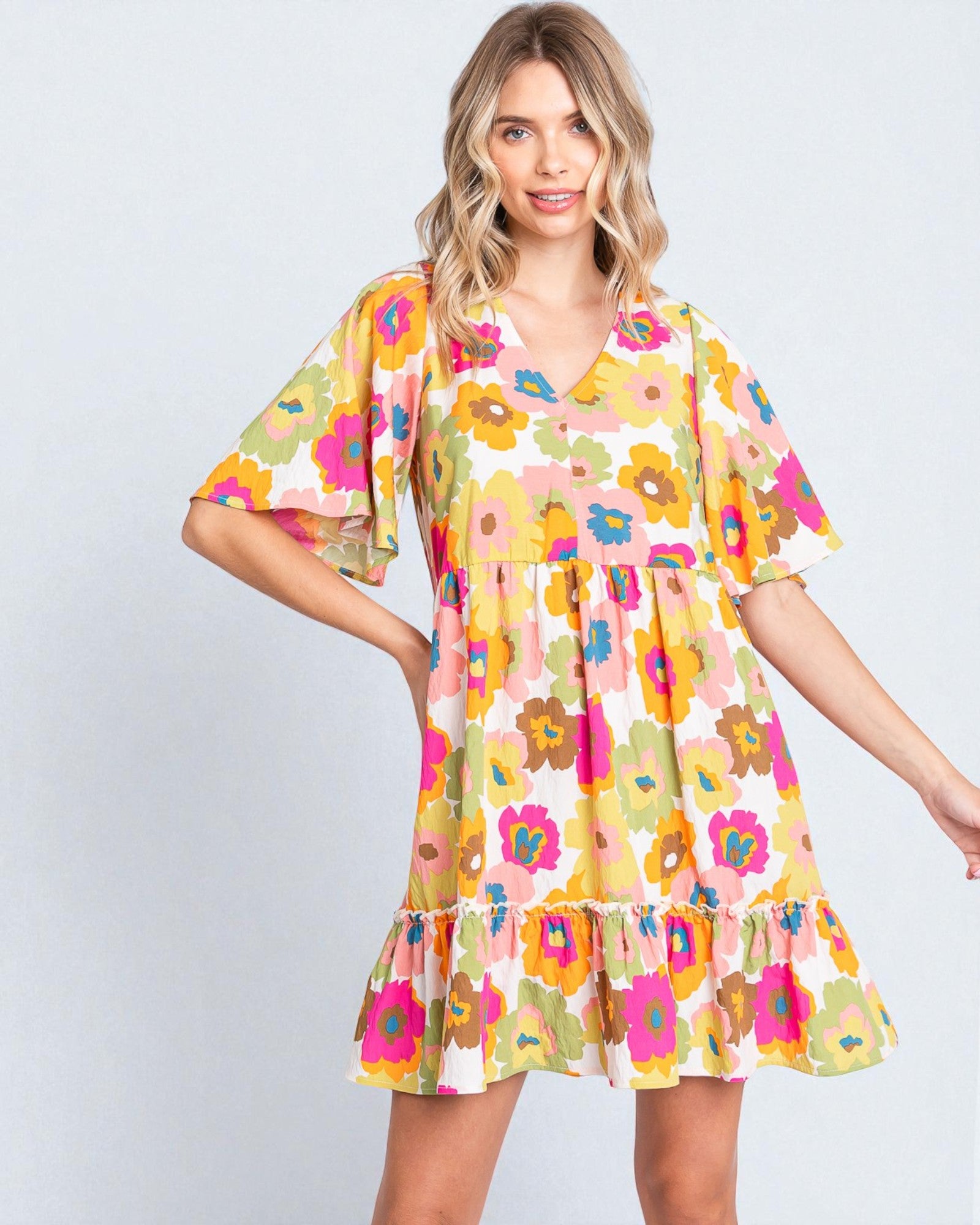 Woman wearing a colorful floral dress against a plain background