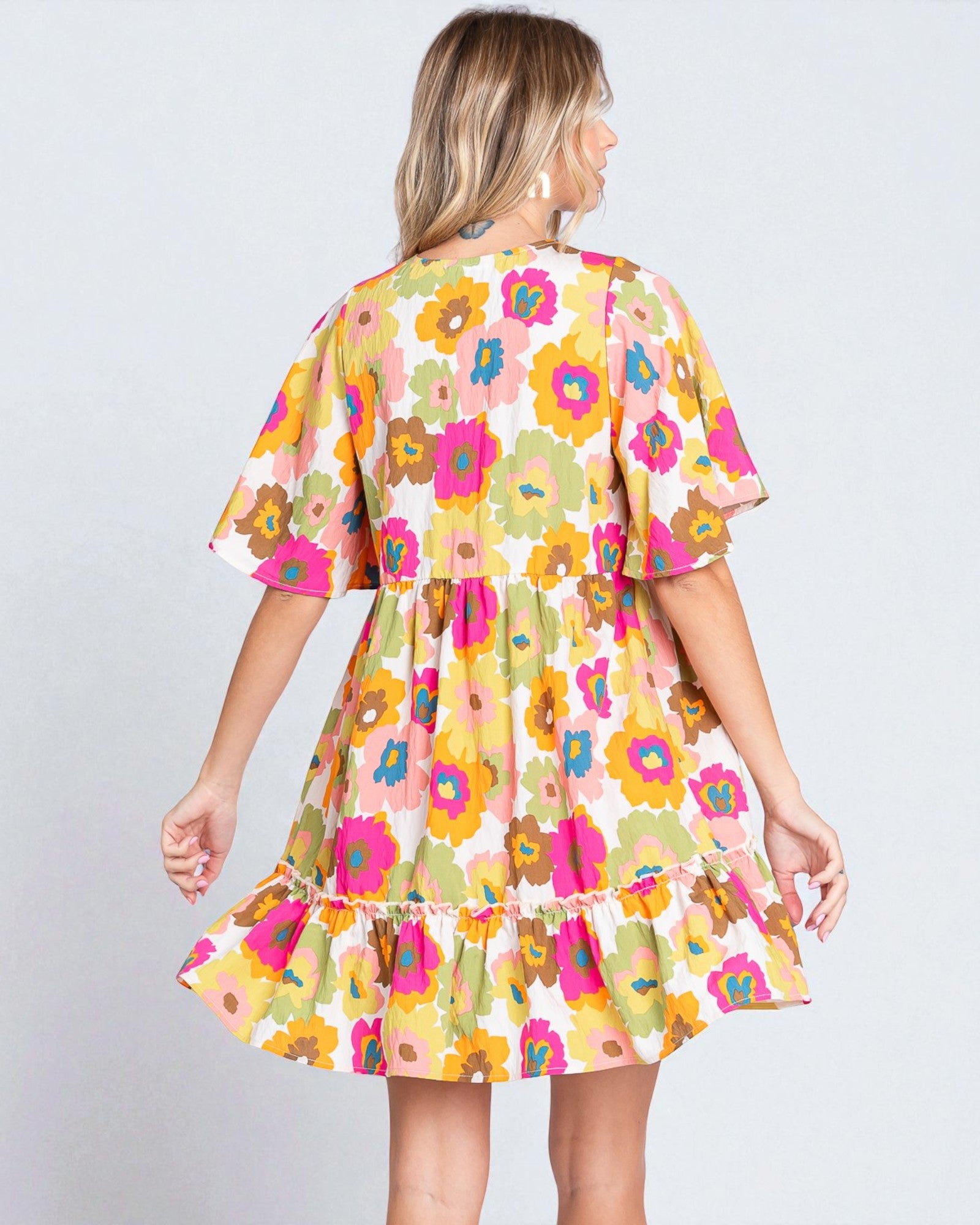 Woman wearing a colorful floral dress on a plain background