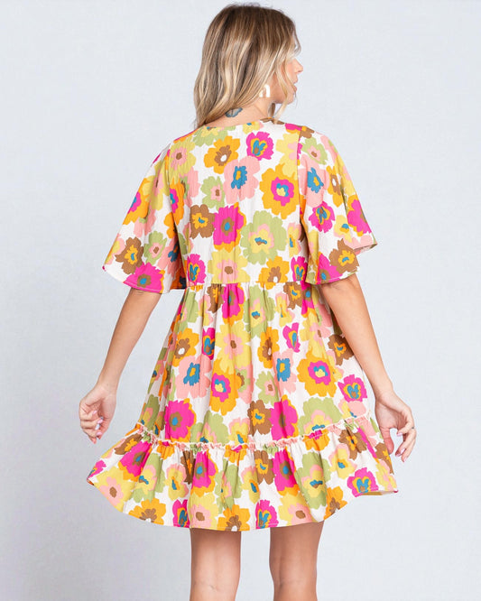 Woman wearing a colorful floral dress on a plain background