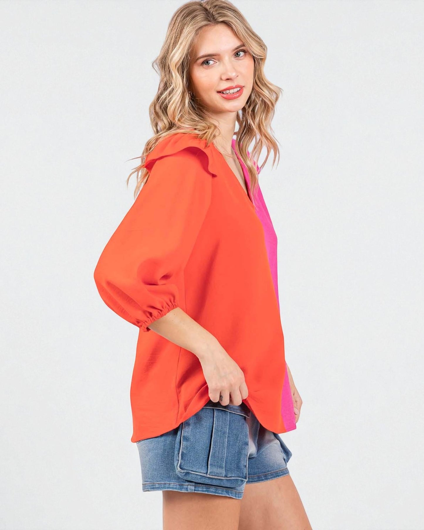 Woman wearing an orange blouse with a pink inner lining on a white background