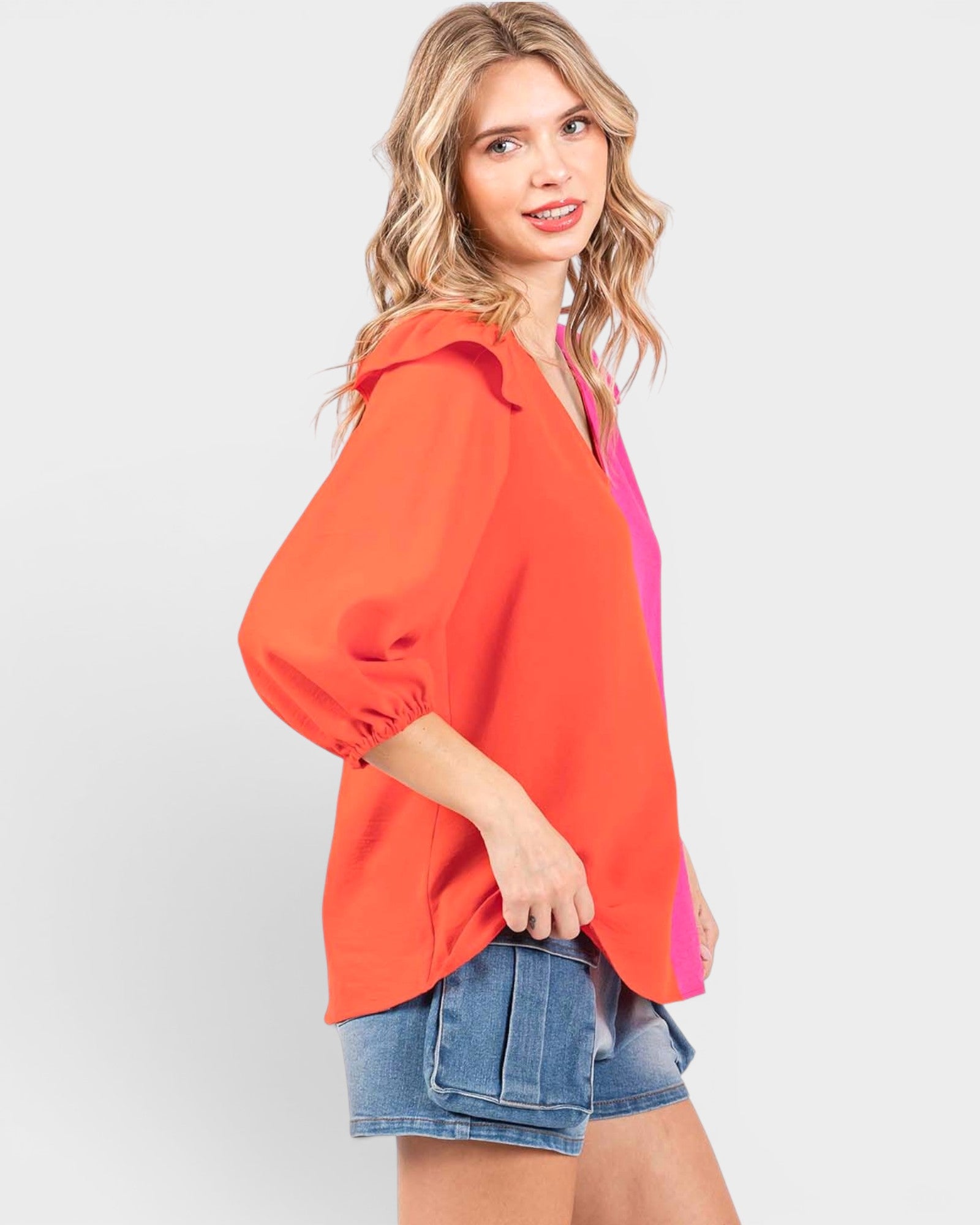 Woman wearing an orange top with a pink accent on a white background