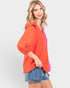 Woman wearing an orange top with a pink accent on a white background