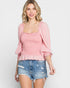 Woman wearing a pink blouse and denim shorts on a white background