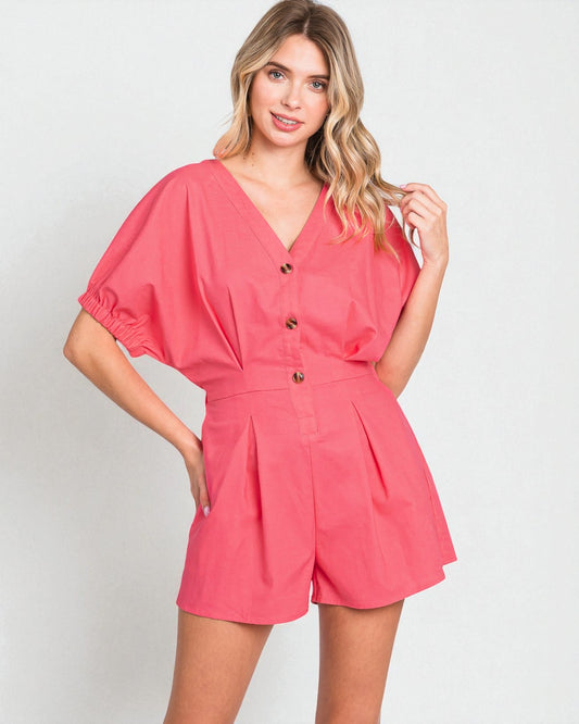 Woman wearing a coral romper against a plain background