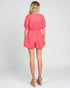 Woman wearing a pink romper on a white background