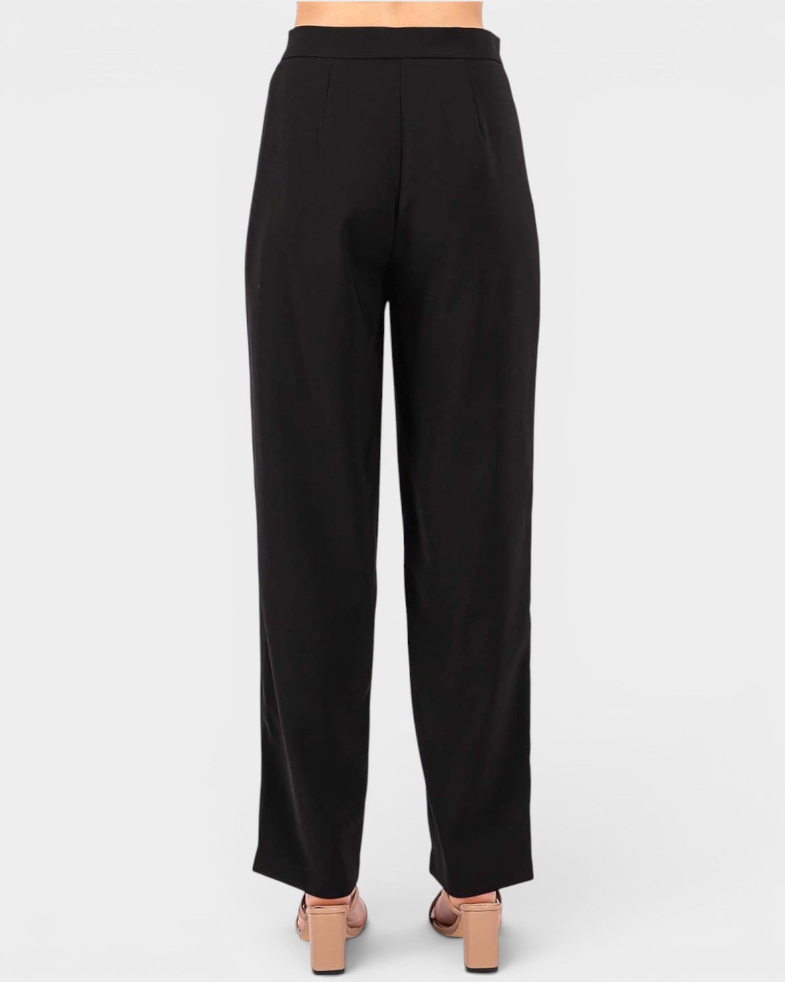 Black wide-leg trousers shown from the back on a model, paired with beige block-heel sandals against a light gray studio background.