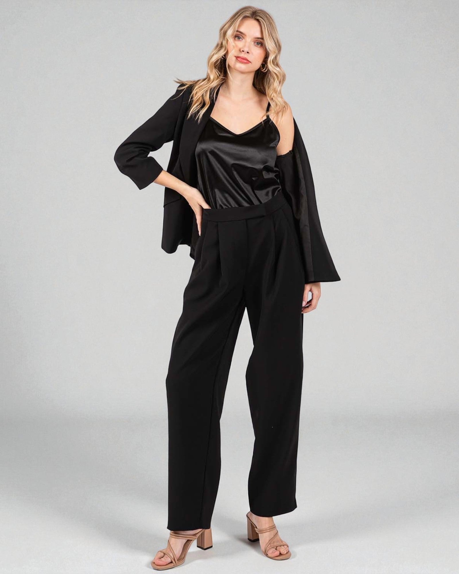 Woman wearing a black outfit with a jacket on a gray background