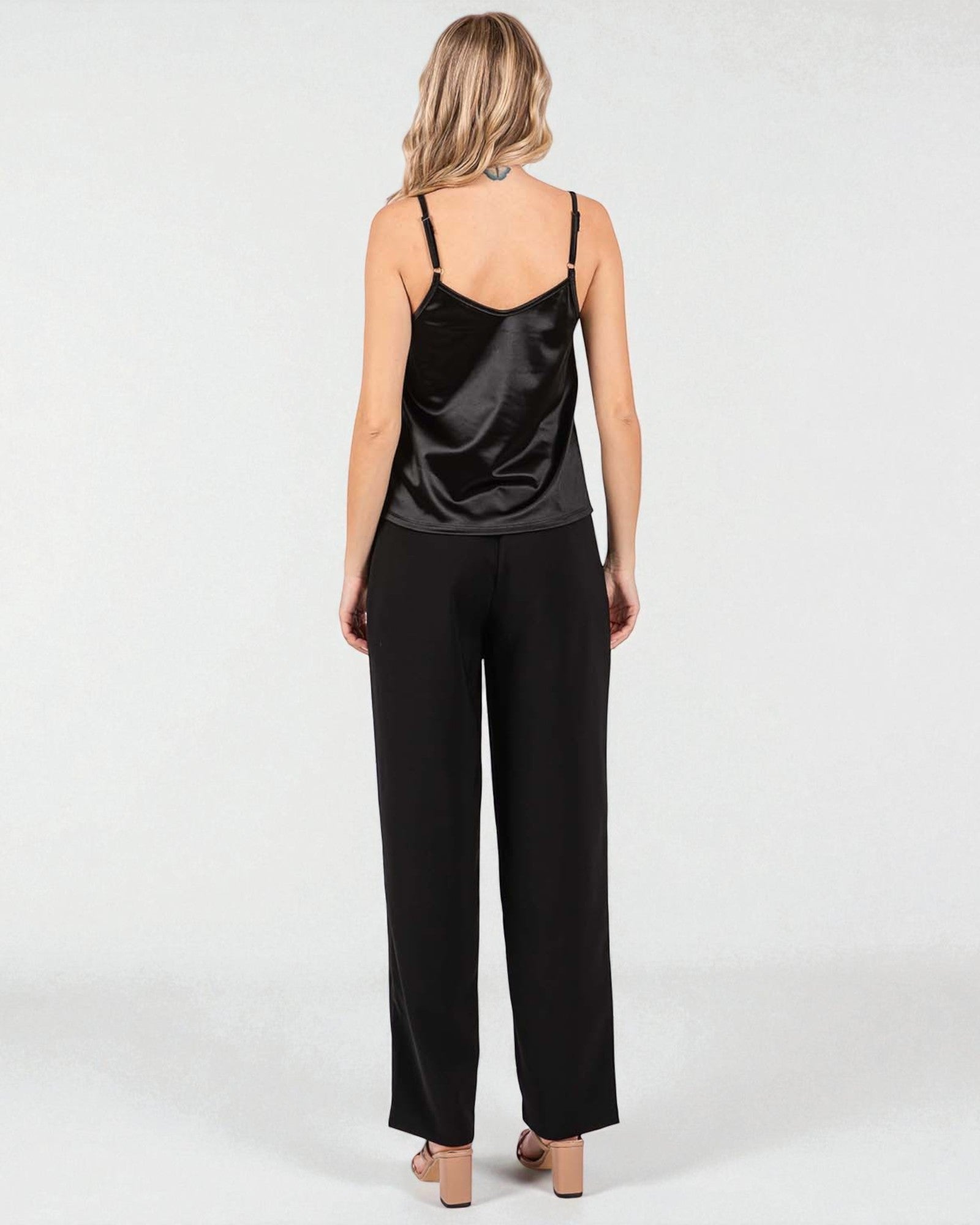 Woman wearing a black satin slip dress on a white background