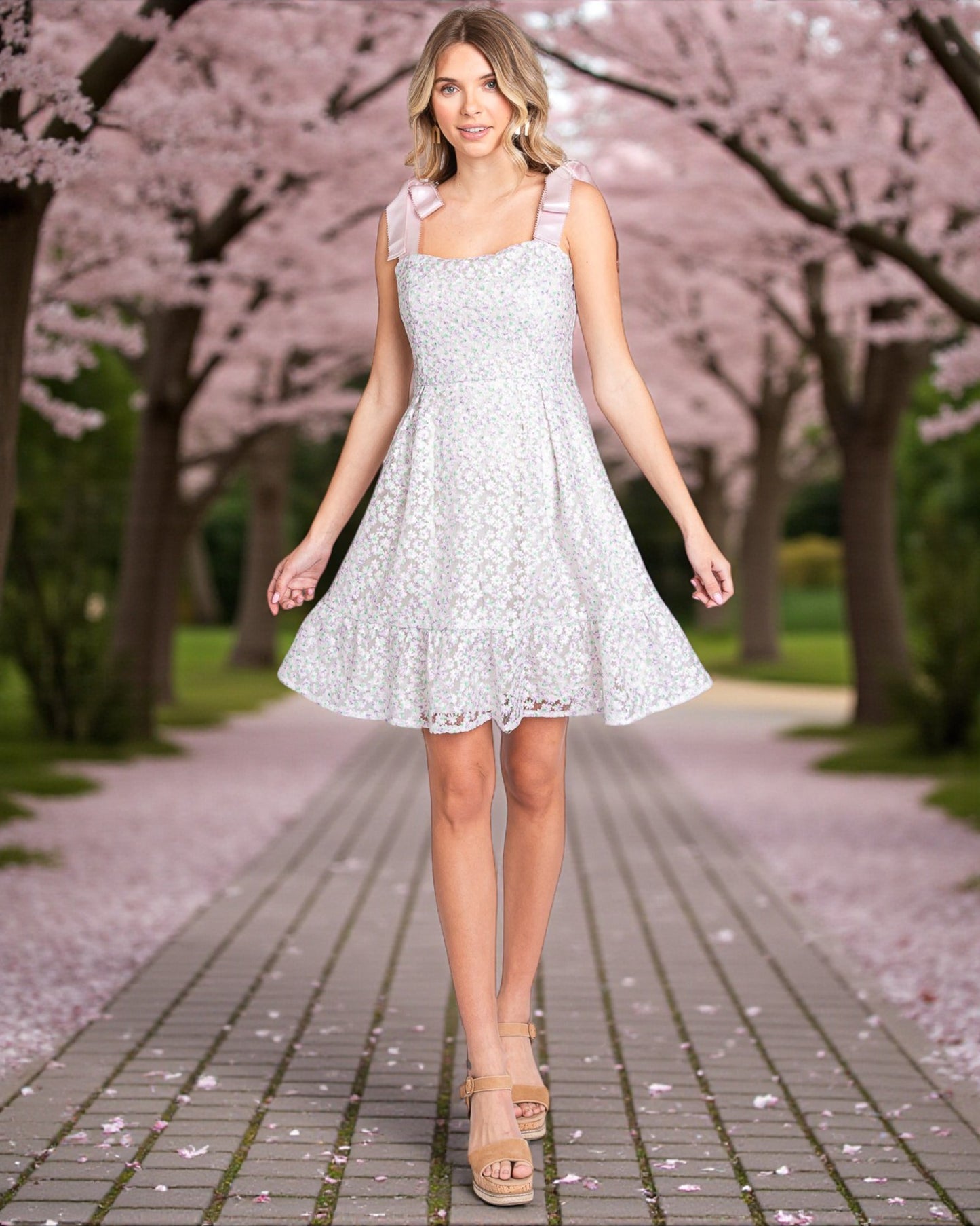 Woman in a light blue floral dress walking under cherry blossom trees