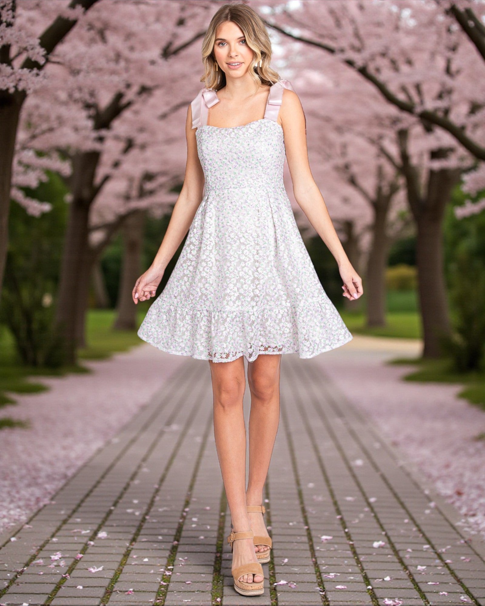 Woman in a light blue floral dress walking under cherry blossom trees