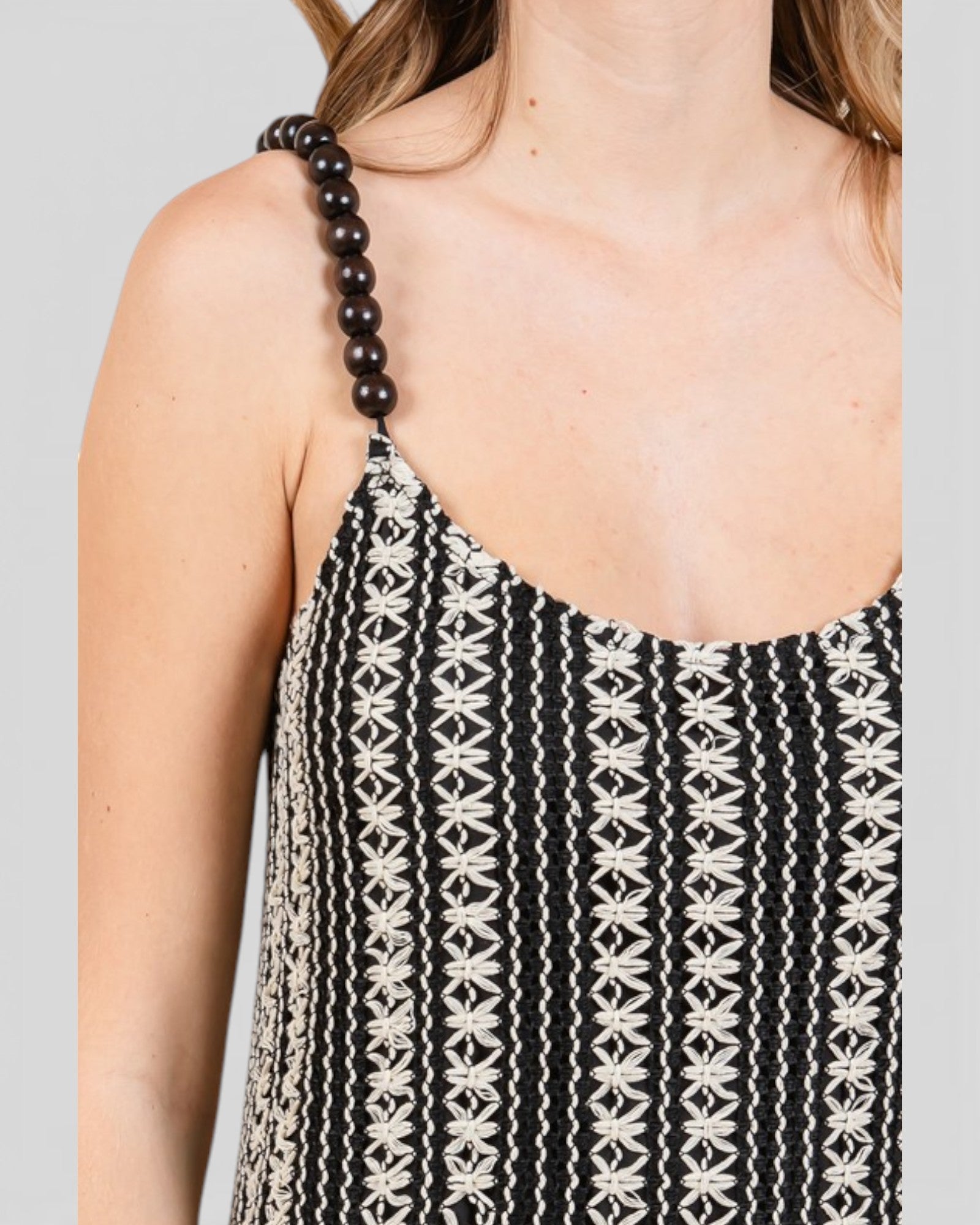 Black and white patterned dress with bead shoulder straps on a plain background