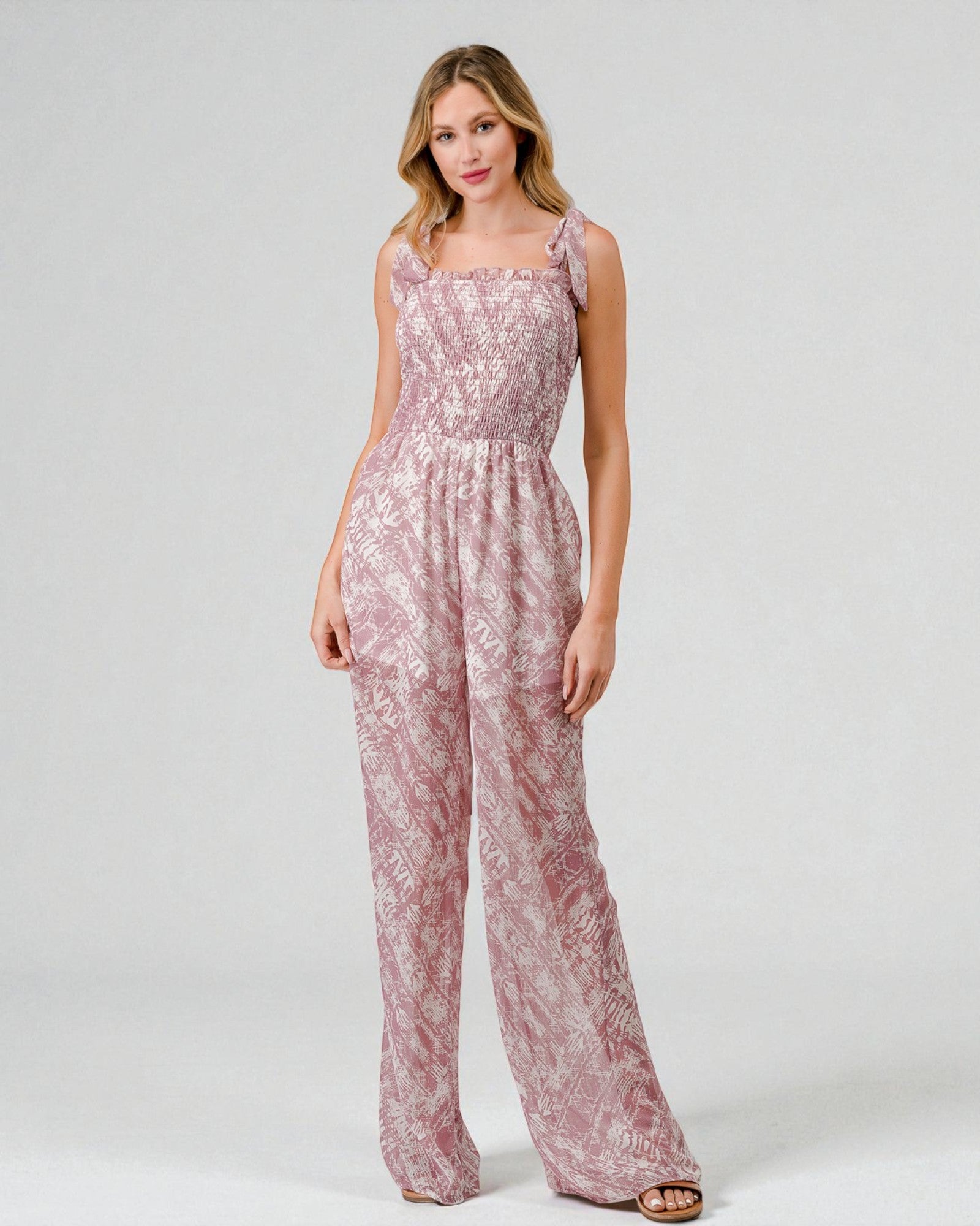Woman wearing a pink floral jumpsuit on a white background