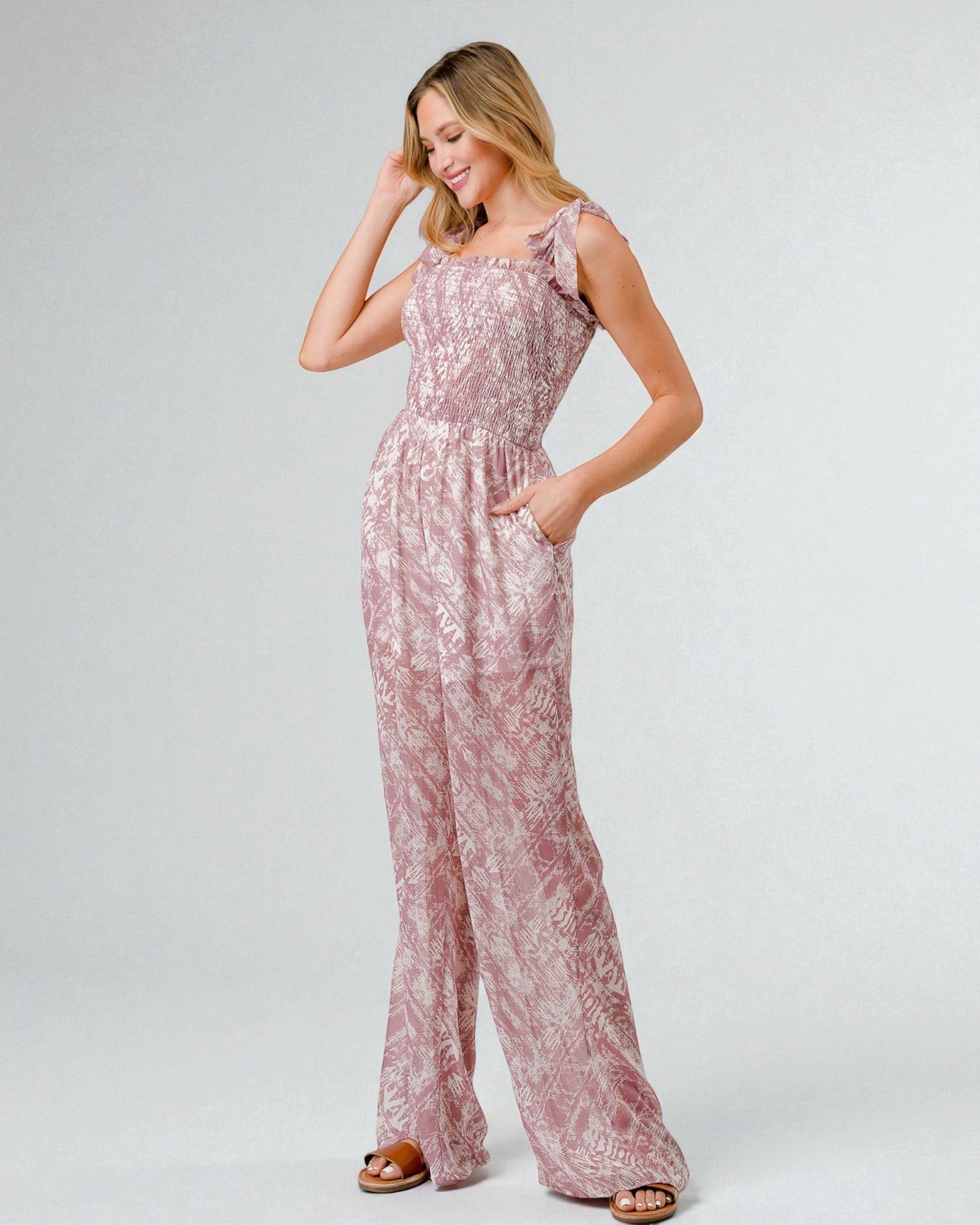 Woman wearing a pink floral jumpsuit on a white background