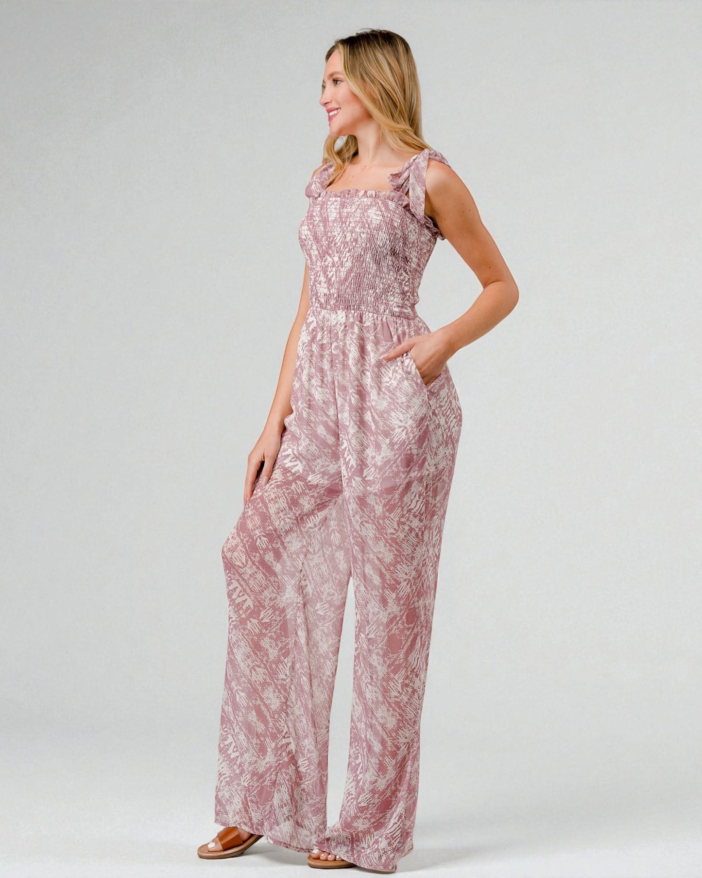 Woman wearing a pink floral jumpsuit on a white background