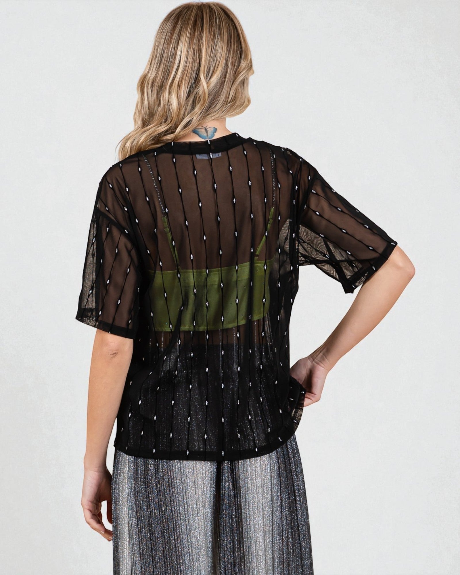 Woman wearing a sheer black top with a green panel on a white background