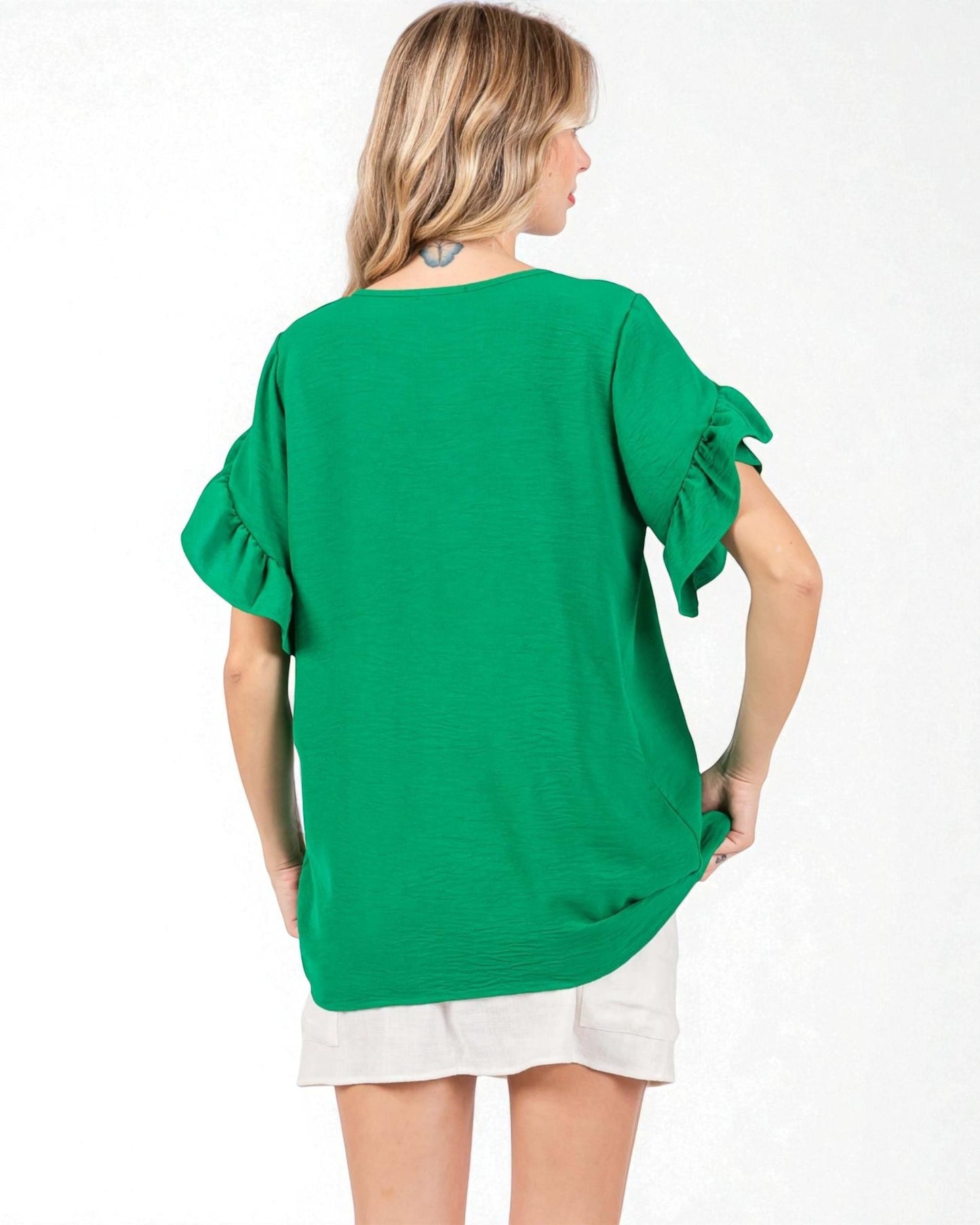 Woman wearing a green blouse with ruffled sleeves on a white background