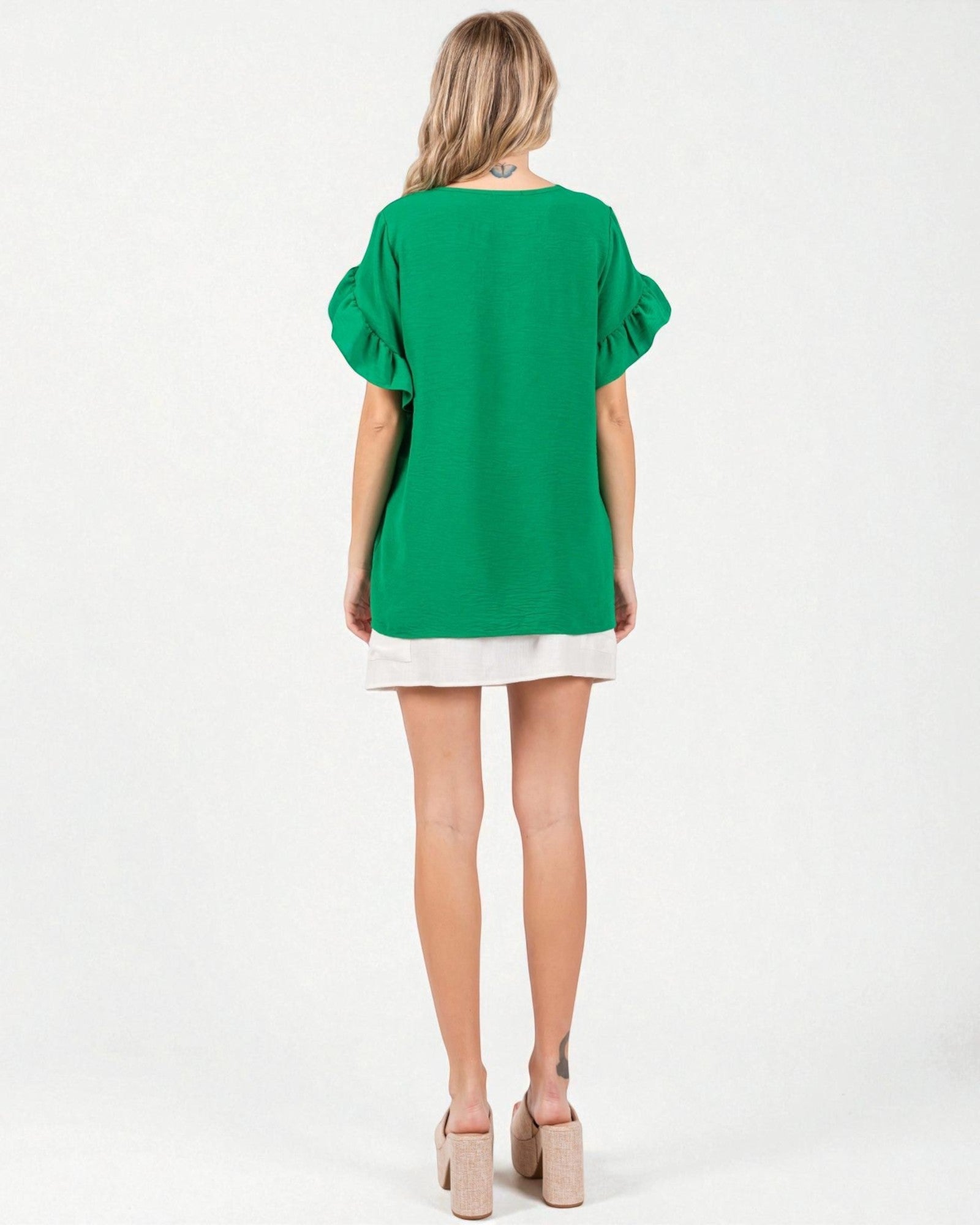 Green dress with white trim worn by a model on a white background