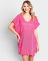 Woman wearing a pink cover-up dress on a plain background
