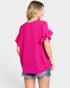 Woman wearing a bright pink blouse with ruffled sleeves on a white background