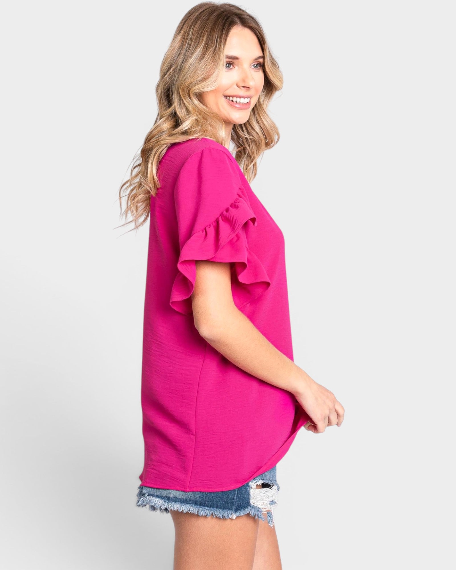 Woman wearing a bright pink blouse with ruffled sleeves on a white background
