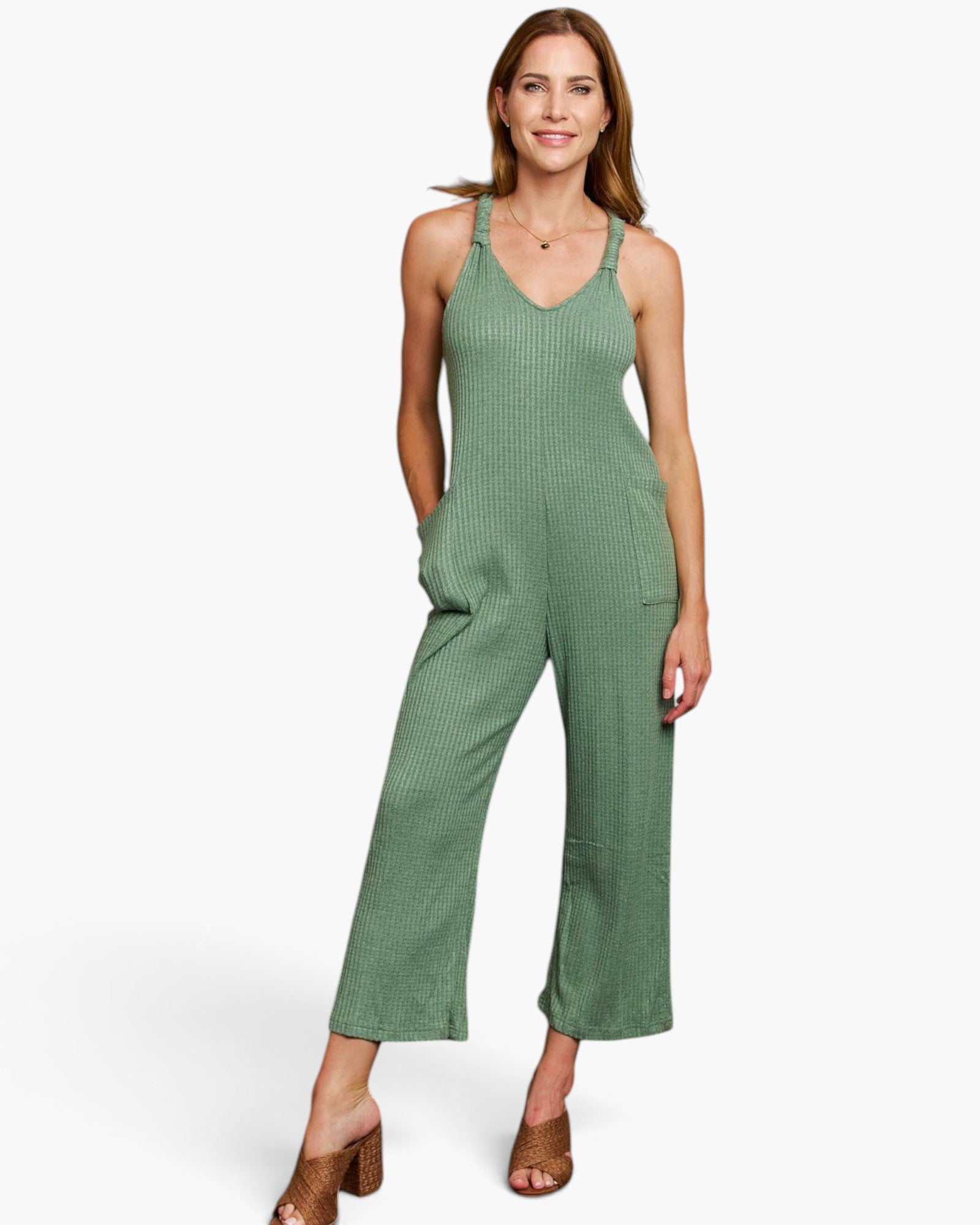 A woman modeling a sage green ribbed sleeveless jumpsuit with wide legs and brown heeled sandals, set against a plain white studio background.