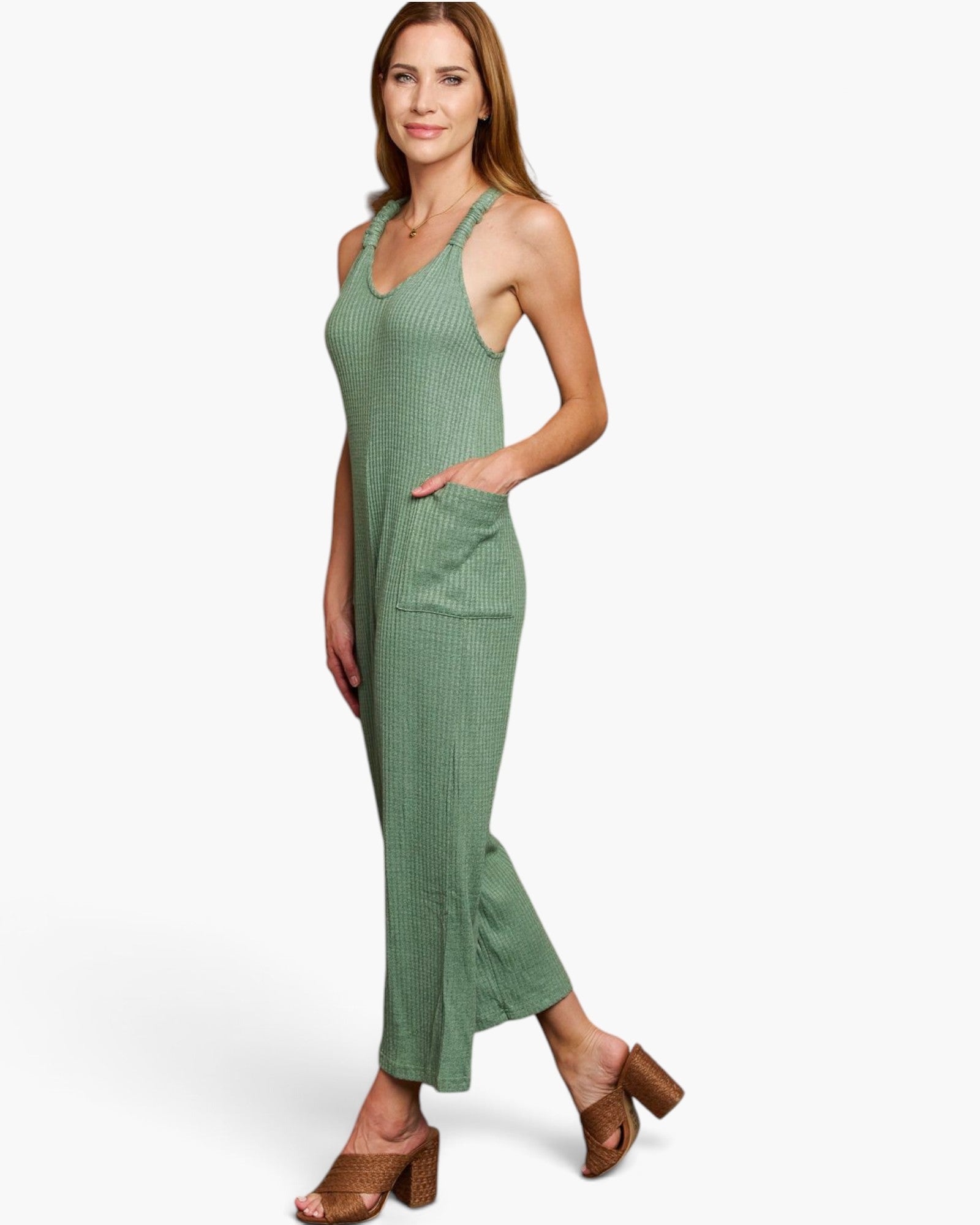 A woman modeling a sleeveless, ribbed green maxi dress with side pockets, paired with brown block-heel sandals, against a plain white studio background.