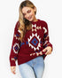 A woman wearing a long-sleeve knit sweater with a Southwestern geometric pattern in burgundy, cream, and blue, paired with light-wash jeans against a plain white background.