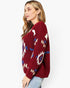 A woman wearing a fuzzy knit sweater with a Southwestern geometric pattern in burgundy, cream, and blue, paired with light-wash jeans against a plain white background.