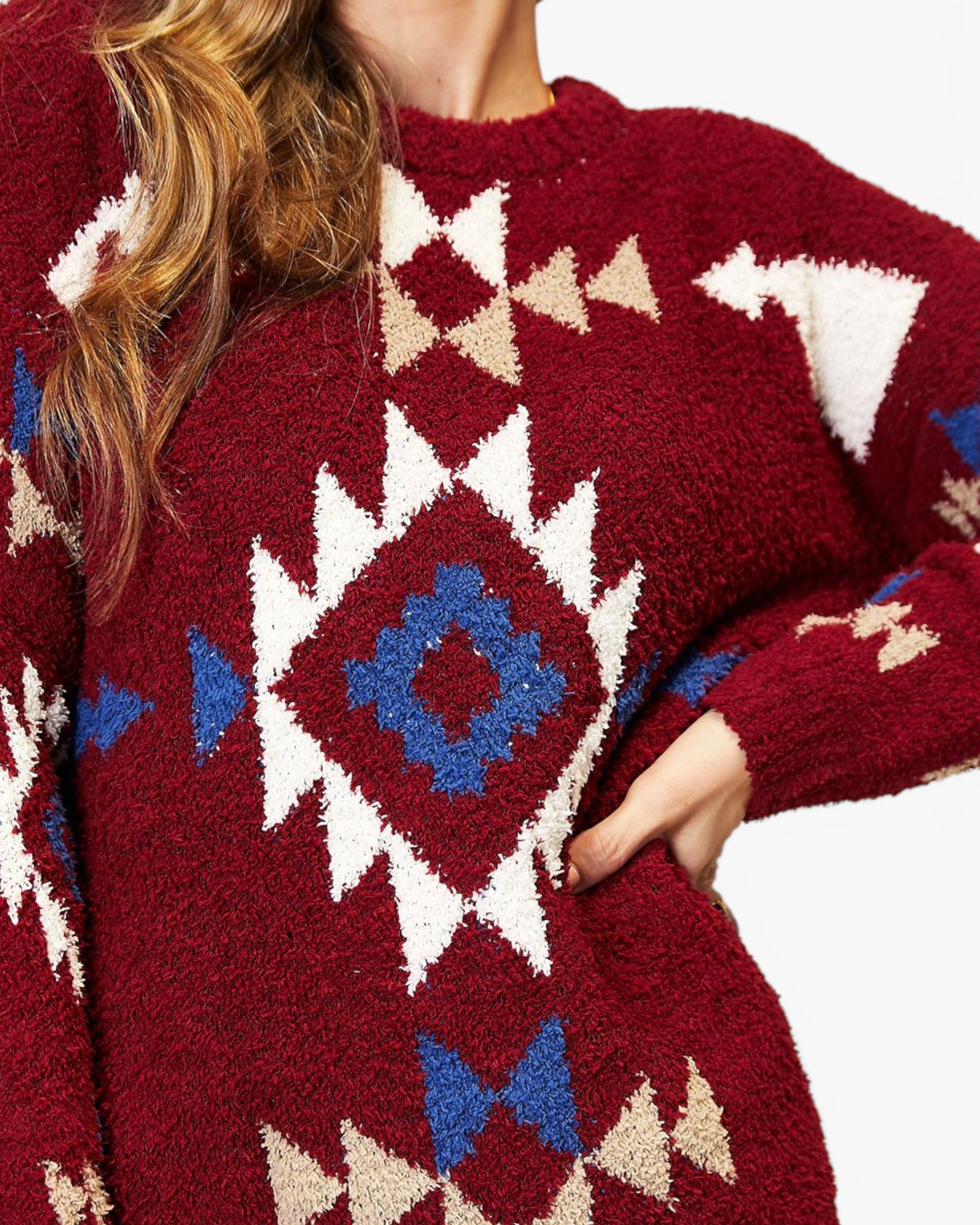 A close-up of a person wearing a fuzzy knit sweater with a Southwestern geometric pattern in burgundy, cream, and blue.