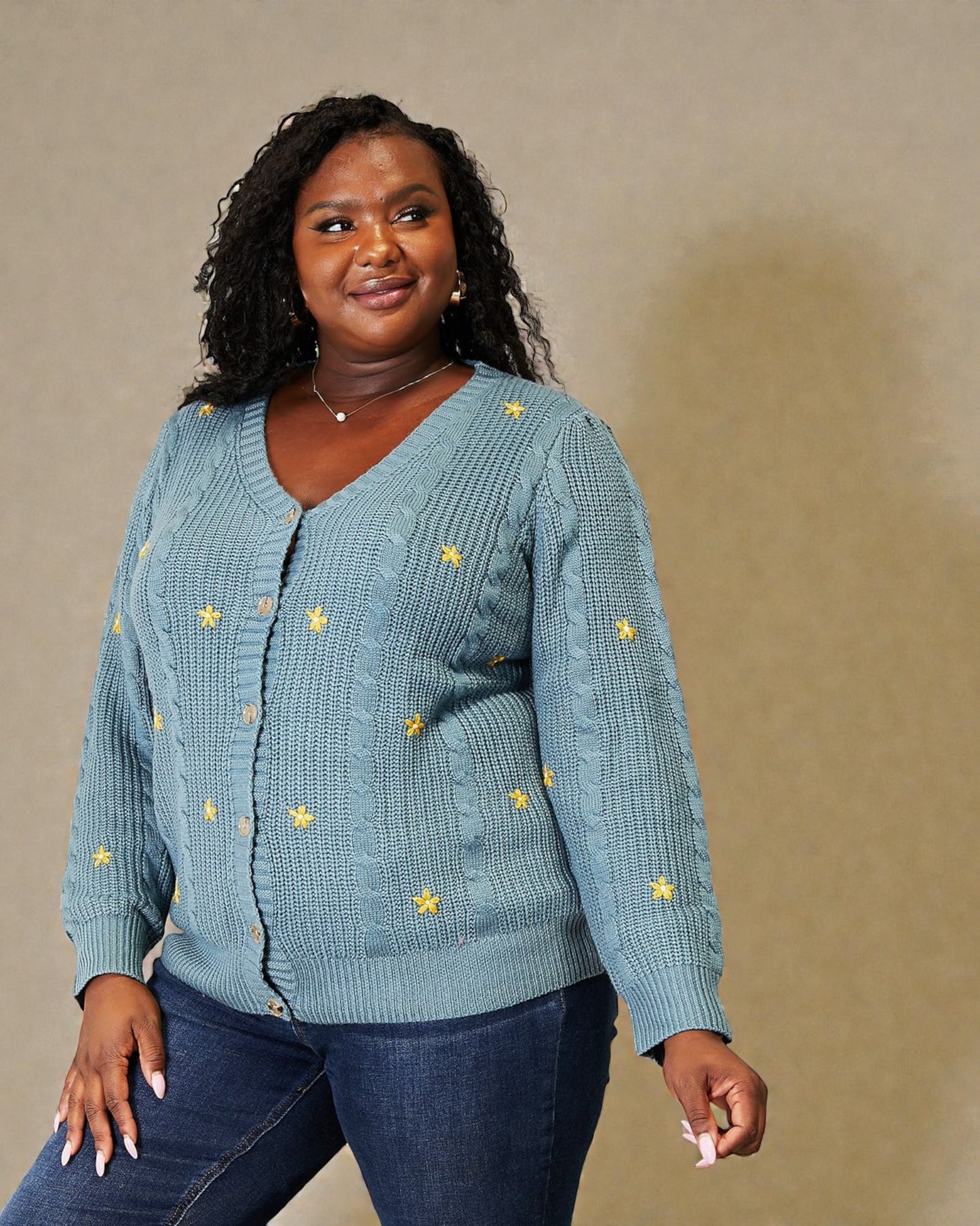 Woman wearing a blue knitted cardigan with yellow star patterns against a beige background