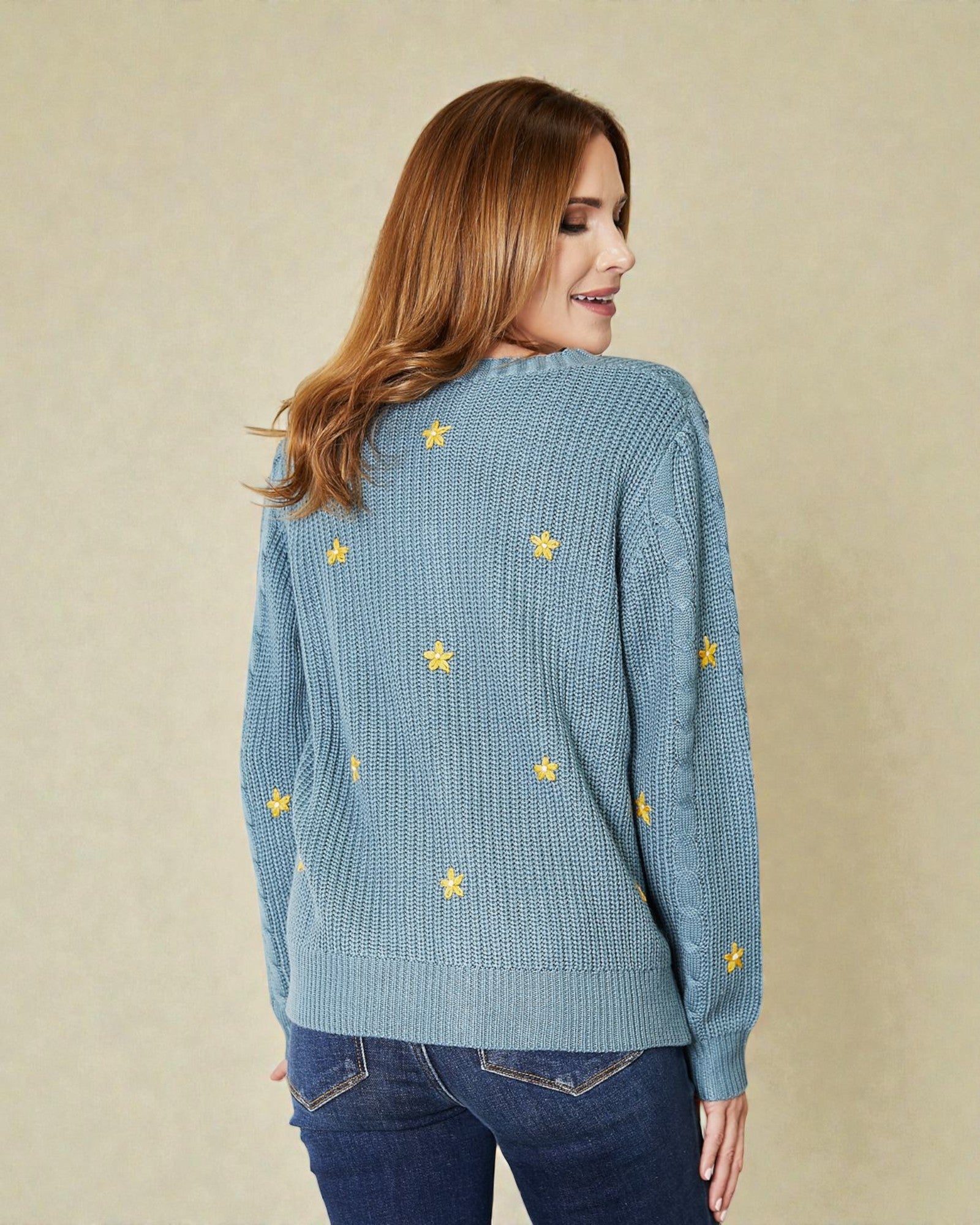 Woman wearing a blue sweater with yellow star patterns on a beige background