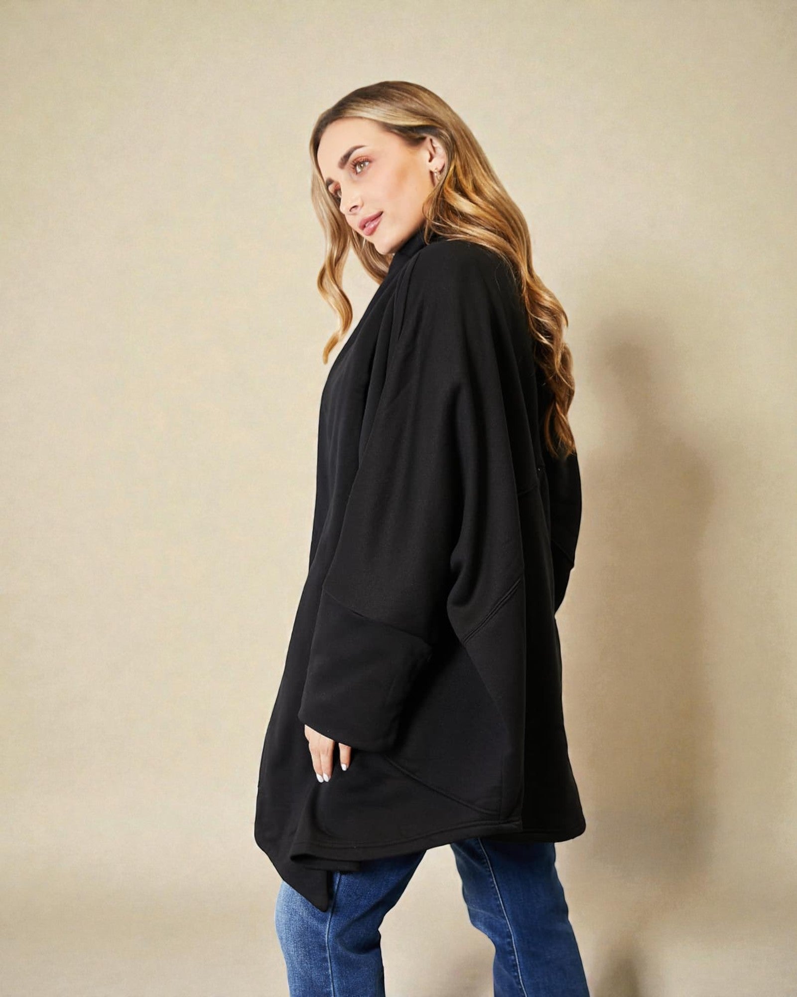 Woman wearing a black oversized sweater against a beige background