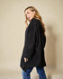 Woman wearing a black oversized sweater against a beige background