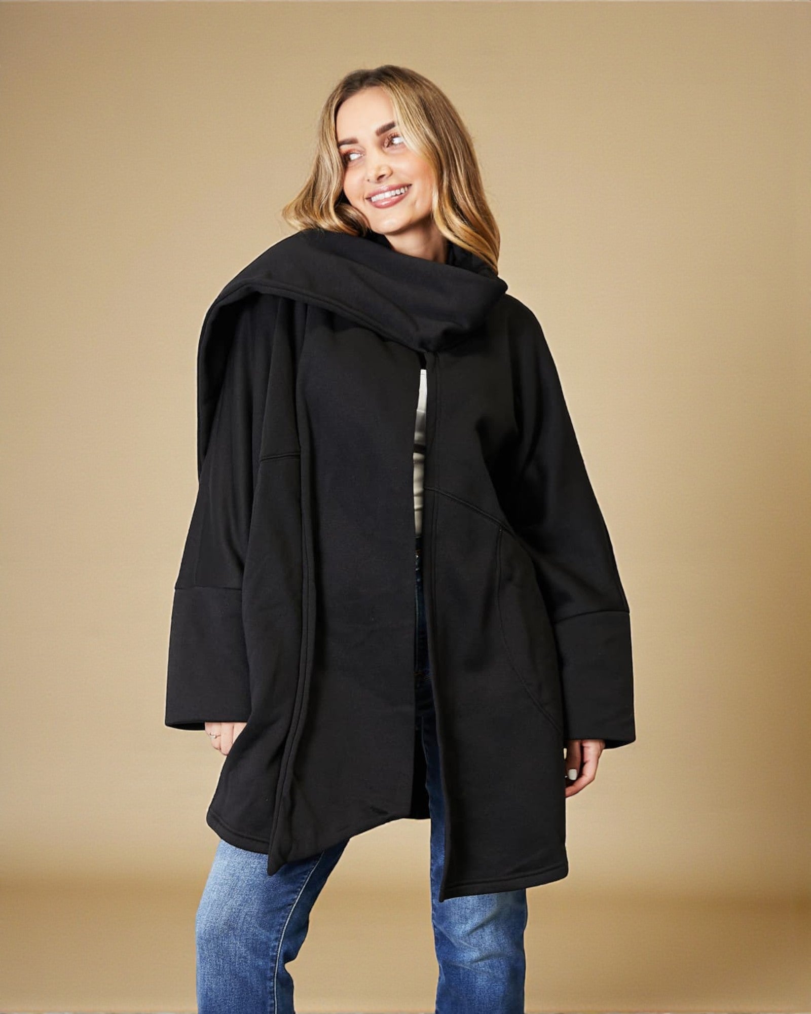 Woman wearing a black coat against a beige background